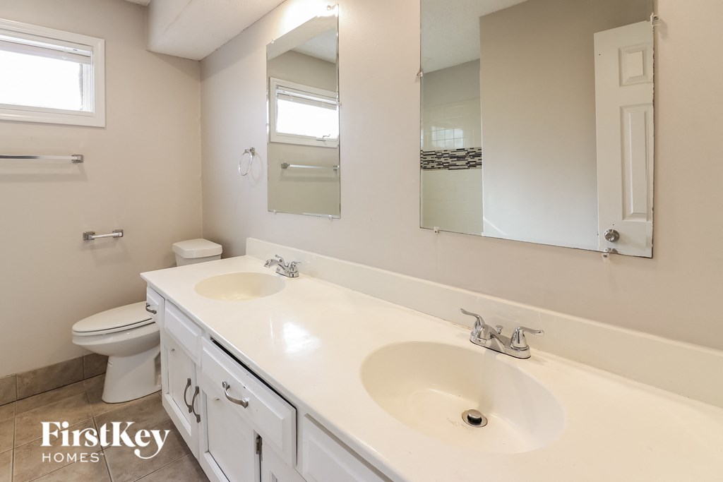 a white bathroom with two sinks and a toilet