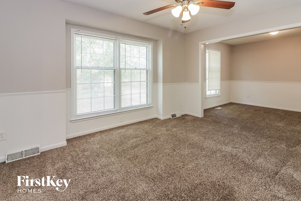an empty living room with carpet and a ceiling fan