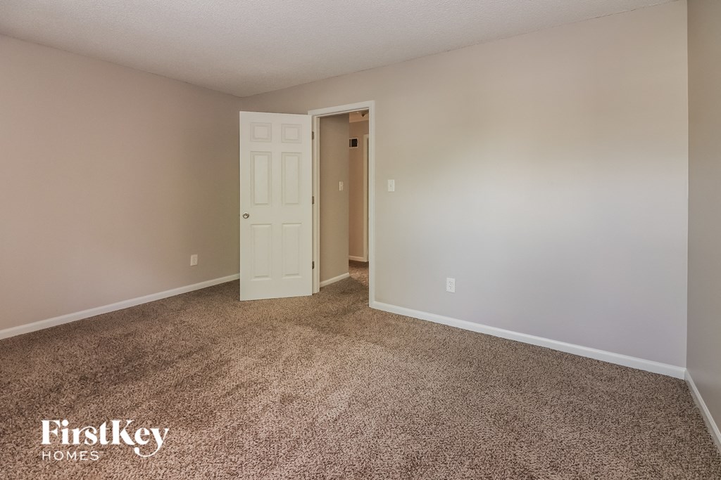a bedroom with a carpeted floor and a door to a closet
