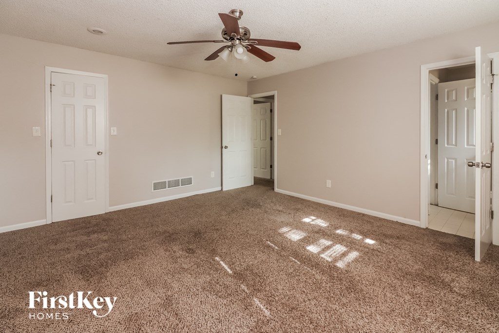 a empty living room with carpet and a ceiling fan