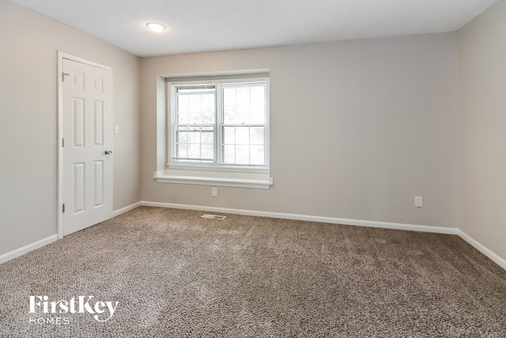 the master bedroom has a carpeted floor and a window