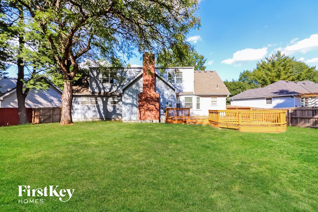 a backyard with a wooden fence and a house in the background