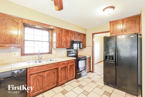 A kitchen with wooden cabinets and a black refrigerator.