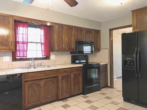 A kitchen with black appliances and wooden cabinets.