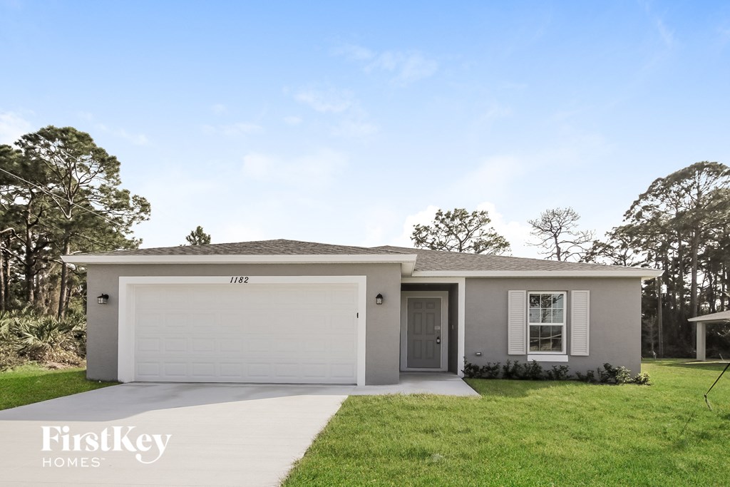 a white house with a lawn and a garage door