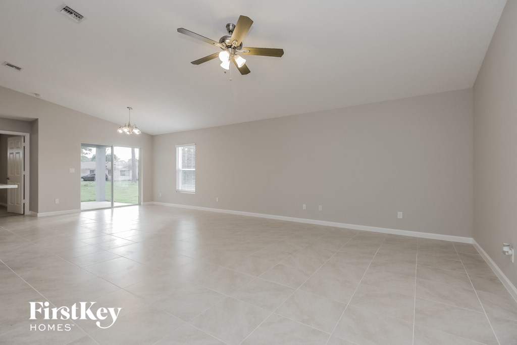 an empty living room with a ceiling fan and tile floor