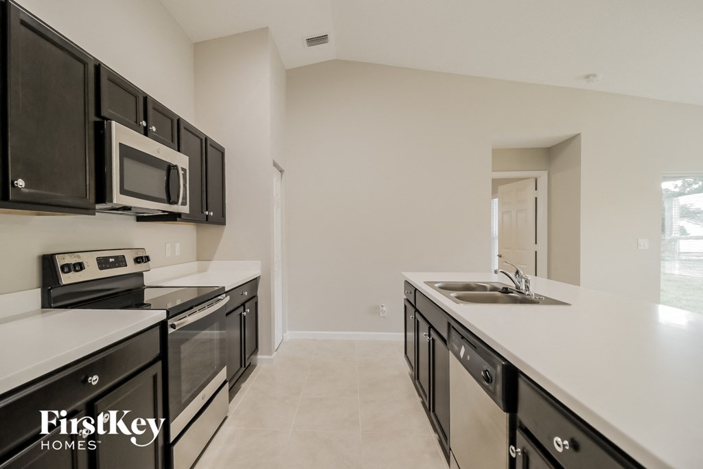 a kitchen with white countertops and black cabinets and a sink and microwave