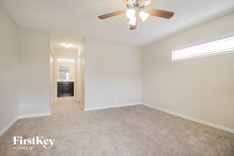 a spacious living room with carpet and a ceiling fan