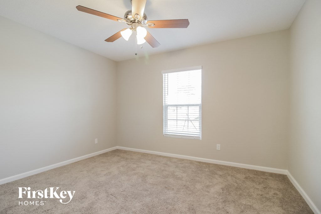 an empty room with a ceiling fan and a window
