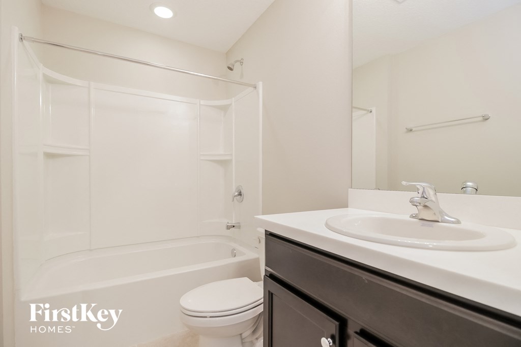 a white bathroom with a sink and toilet and a shower