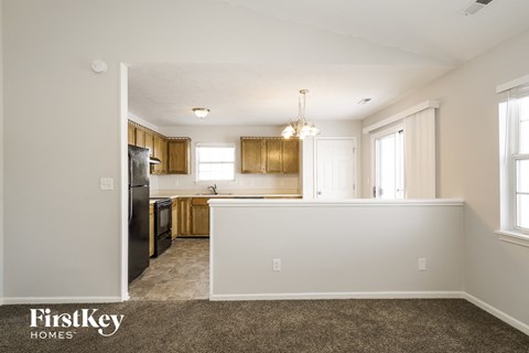 the kitchen and dining area of a white house with wood cabinets