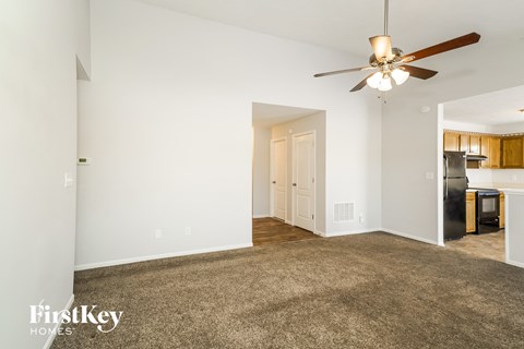 a living room with carpet and a ceiling fan