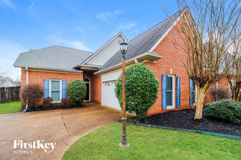 a brick house with blue shutters and a lawn