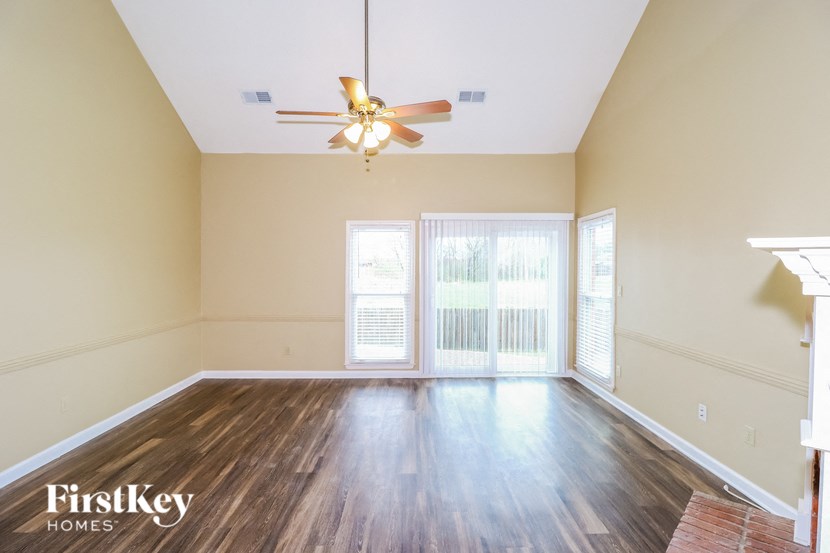 an empty living room with wood floors and a ceiling fan