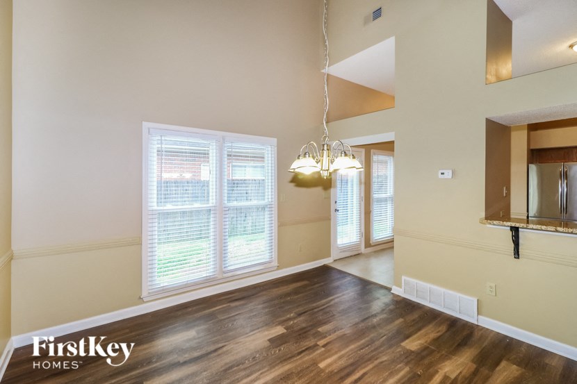 an empty living room with a large window and a chandelier