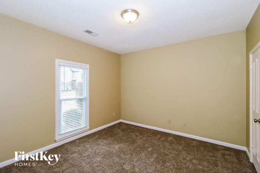 the upstairs bedroom with carpeted flooring and a window