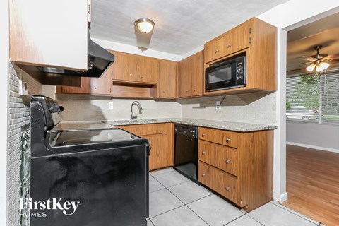 A kitchen with wooden cabinets and a black fridge.