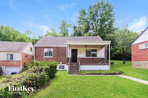 a small brick house with a lawn and a porch