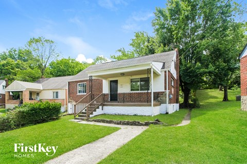 the front of a brick house with a lawn and trees