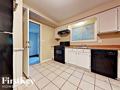 A kitchen with white cabinets and black appliances.