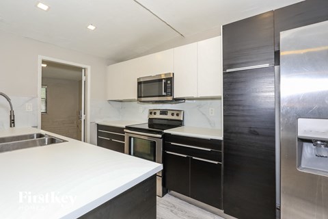 A modern kitchen with a stainless steel refrigerator and black cabinets.
