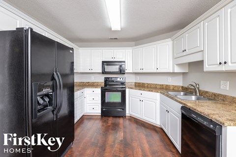 a kitchen with white cabinets and a black refrigerator