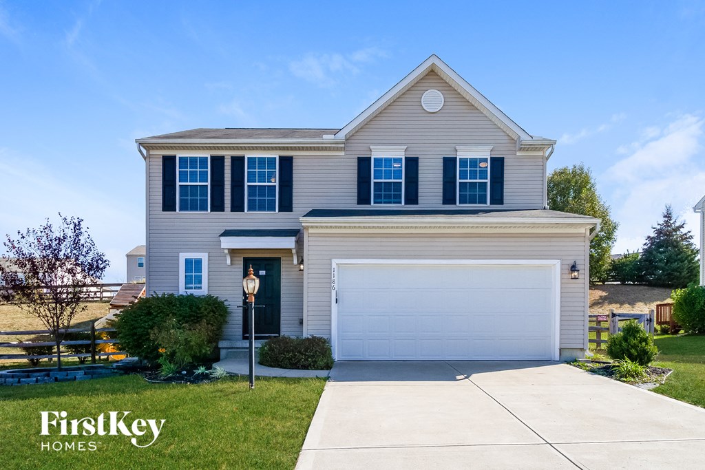 a beige house with a white garage door in front of a lawn