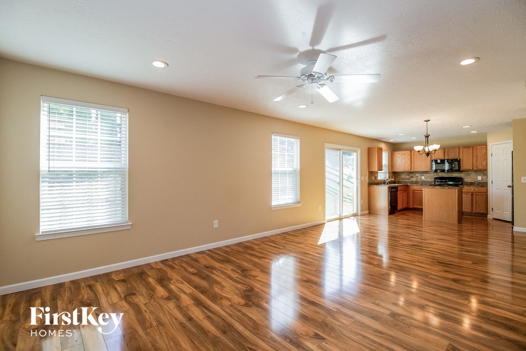 an empty living room and kitchen with wood floors and a ceiling fan
