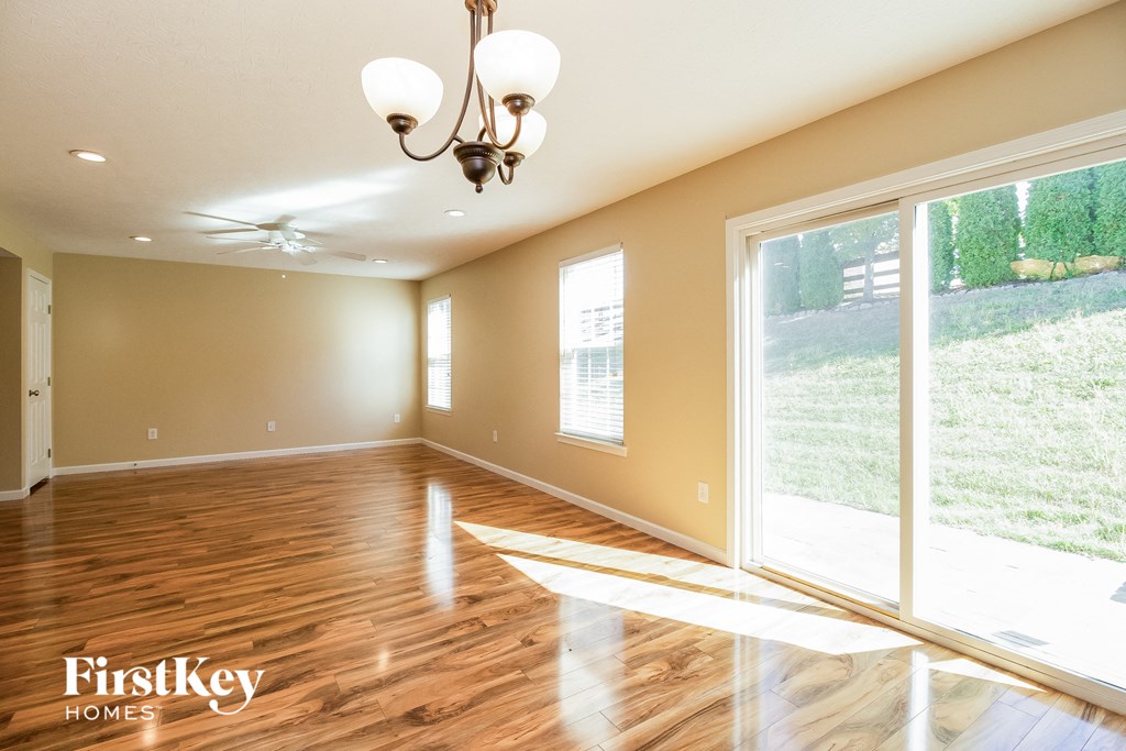 an empty living room with wood floors and large windows