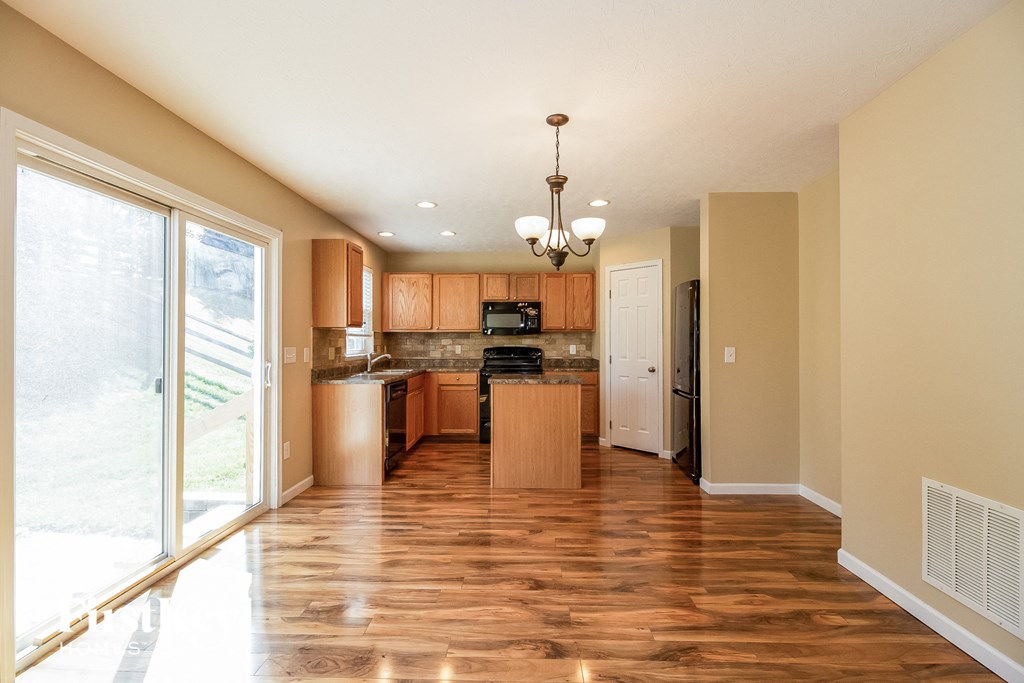 an empty kitchen with wood flooring and a large window