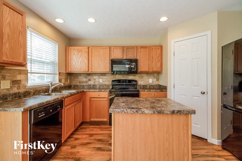 a kitchen with wood cabinets and granite counter tops and black appliances