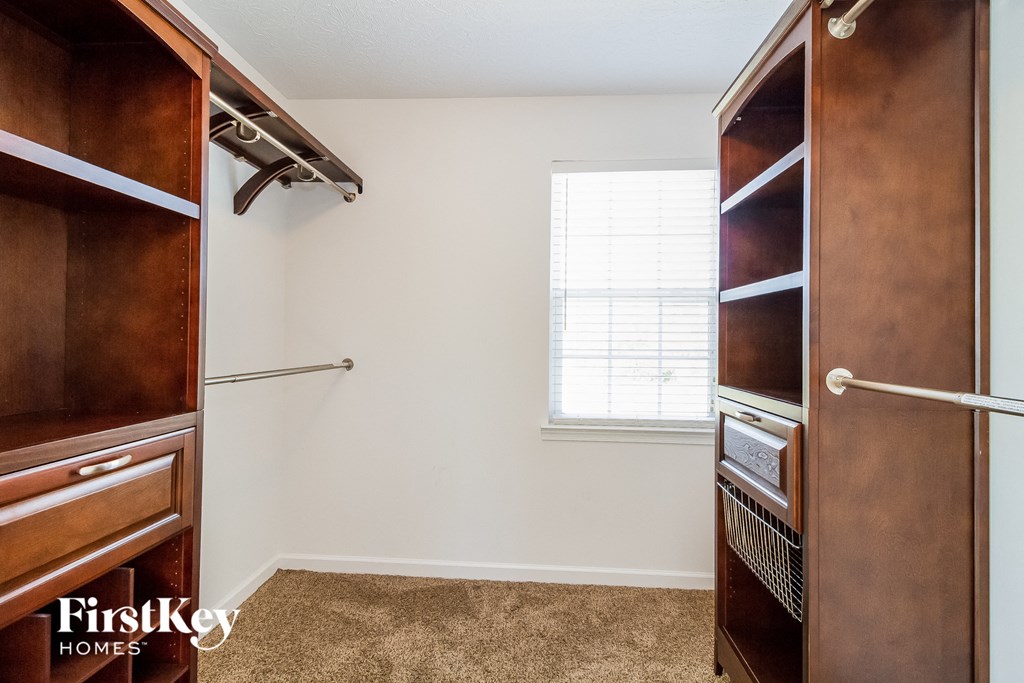 a walk in closet with a window and a dresser and a large closet organizer