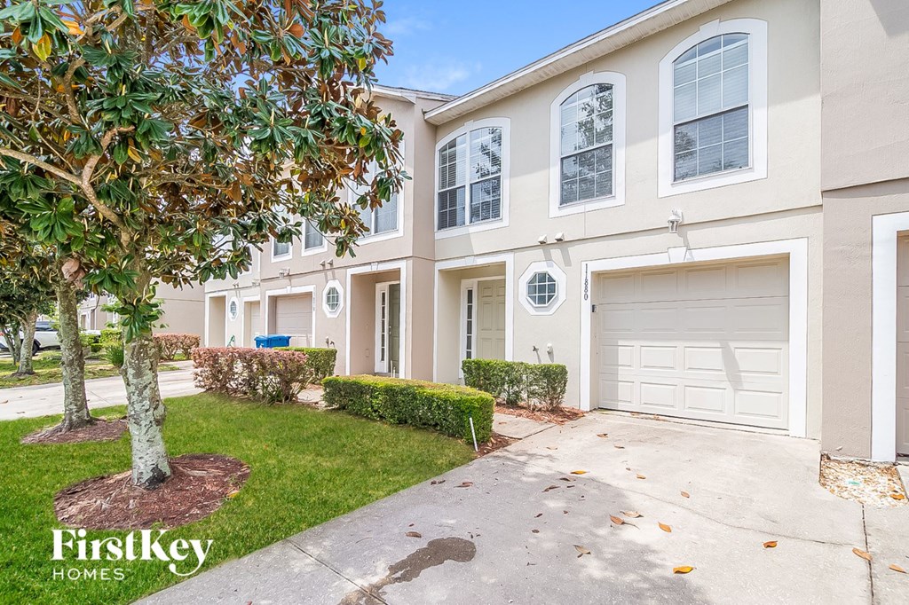 a white house with a white garage door and a tree