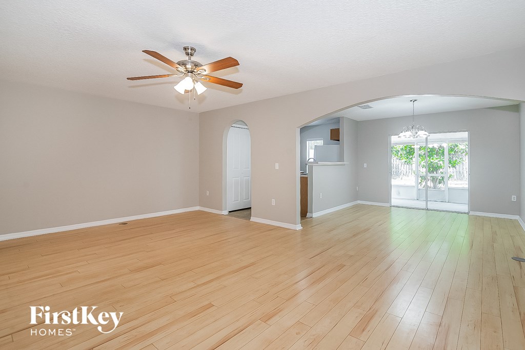 the living room and dining room with hardwood floors and a ceiling fan