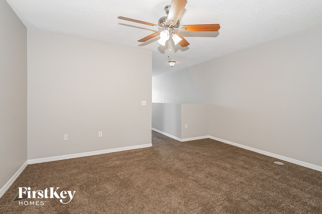 a empty room with a ceiling fan and a carpet