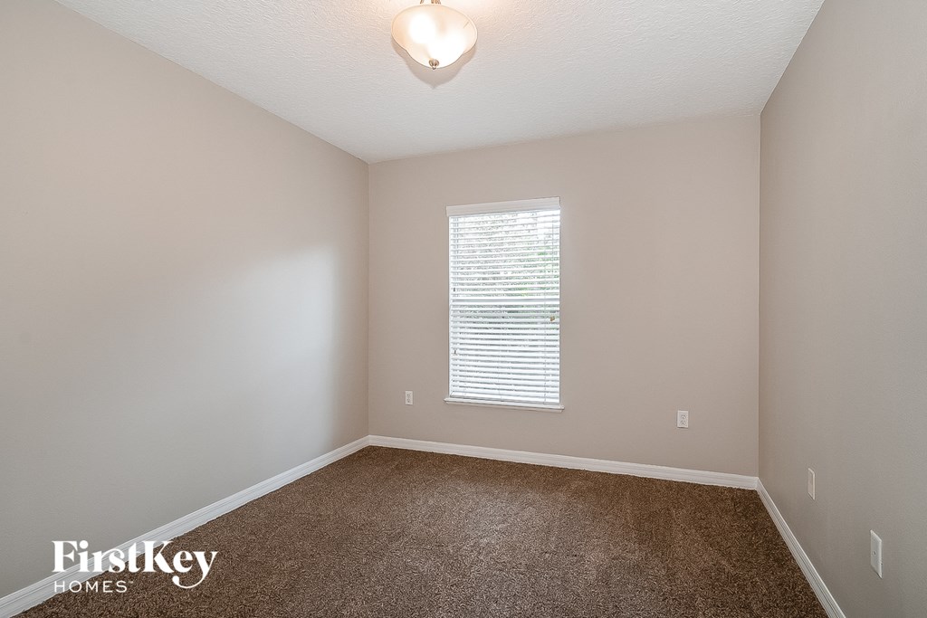 a bedroom with a carpeted floor and a window