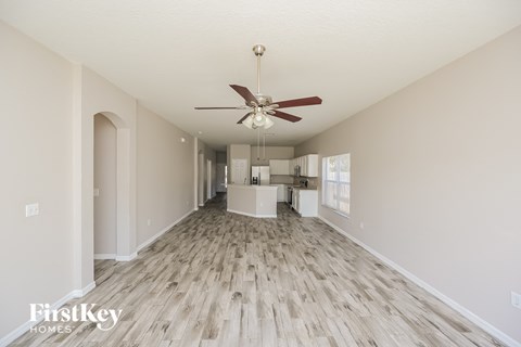 A spacious room with a fan and wooden flooring.