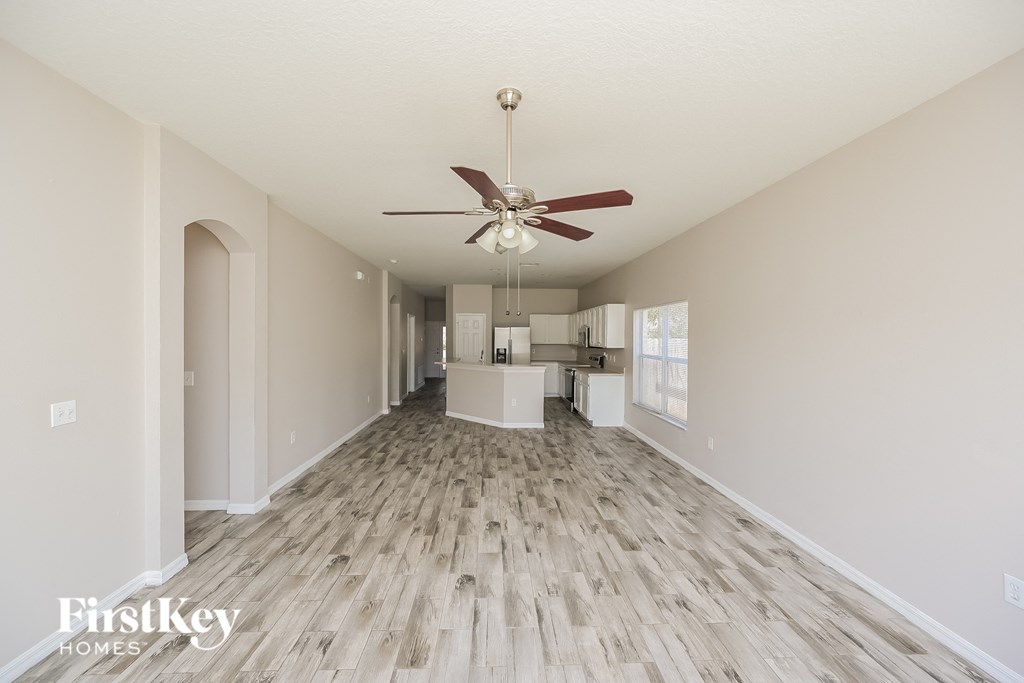 A spacious room with a fan and wooden flooring.