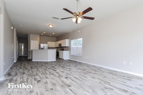 A spacious living room with a ceiling fan and lighting fixtures.