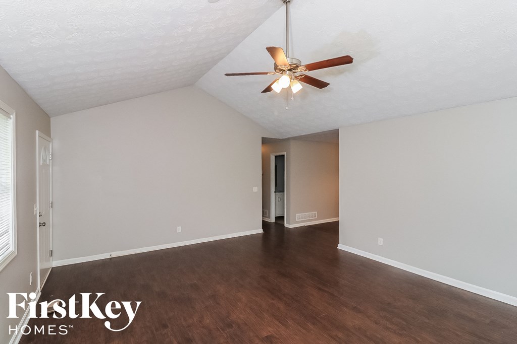 a living room with white walls and a ceiling fan