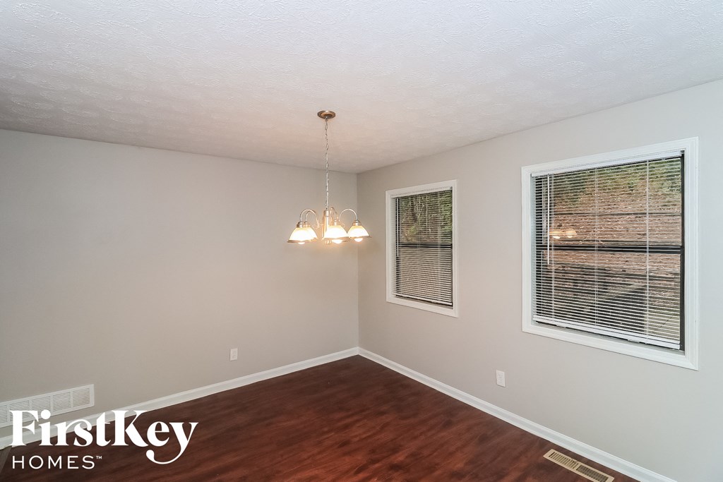 a dining room with a wood floor and two windows