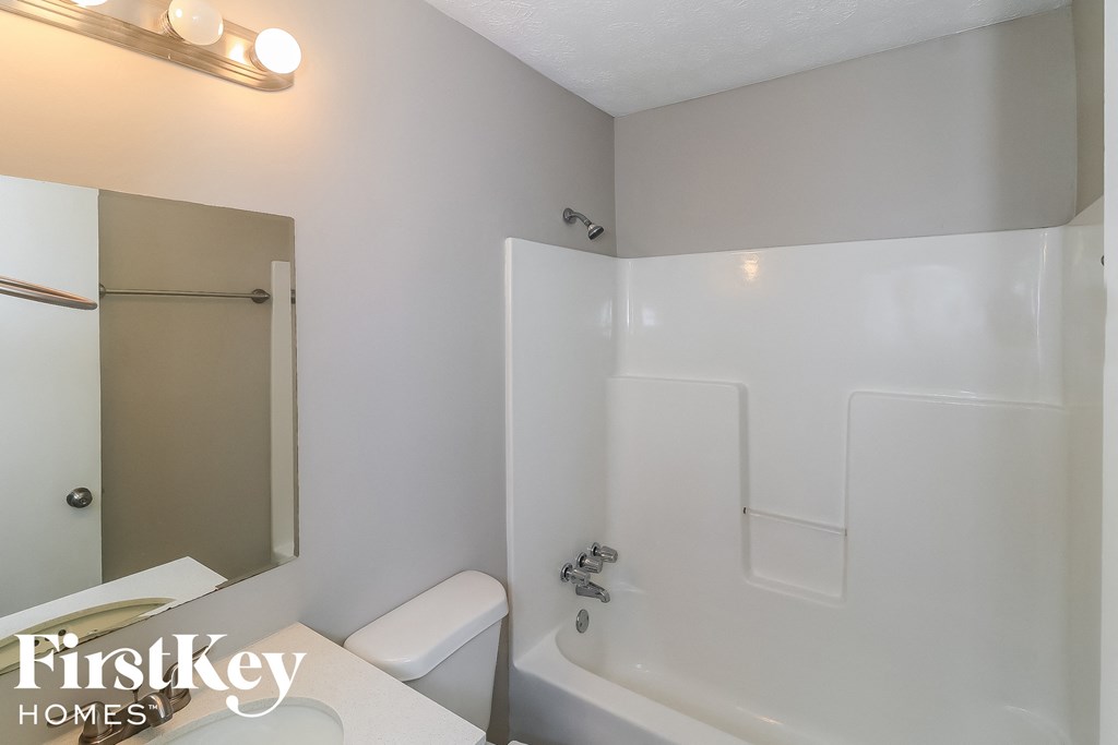 a white bathroom with a tub and a sink and a mirror