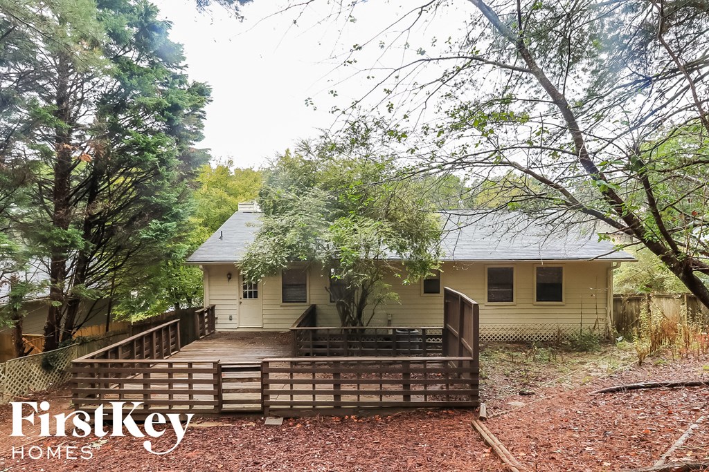 a small yellow house with a deck and a fence