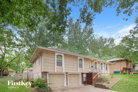 A house with a garage is surrounded by trees.