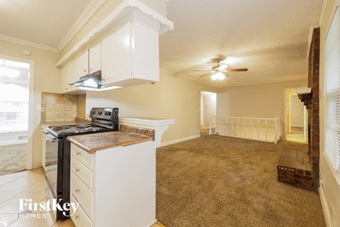 A kitchen with a stove top oven and a ceiling fan.