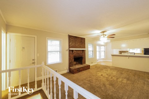 A spacious living room with a fireplace and a carpeted floor.