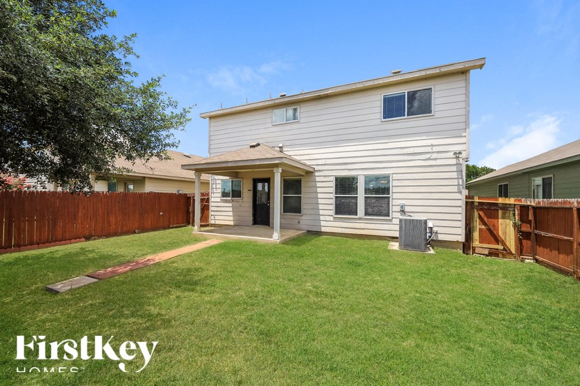 a backyard with a white house and a wooden fence