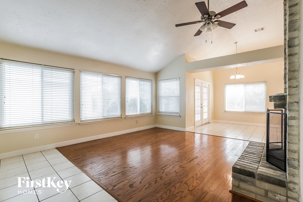 an empty living room with wood floors and a ceiling fan