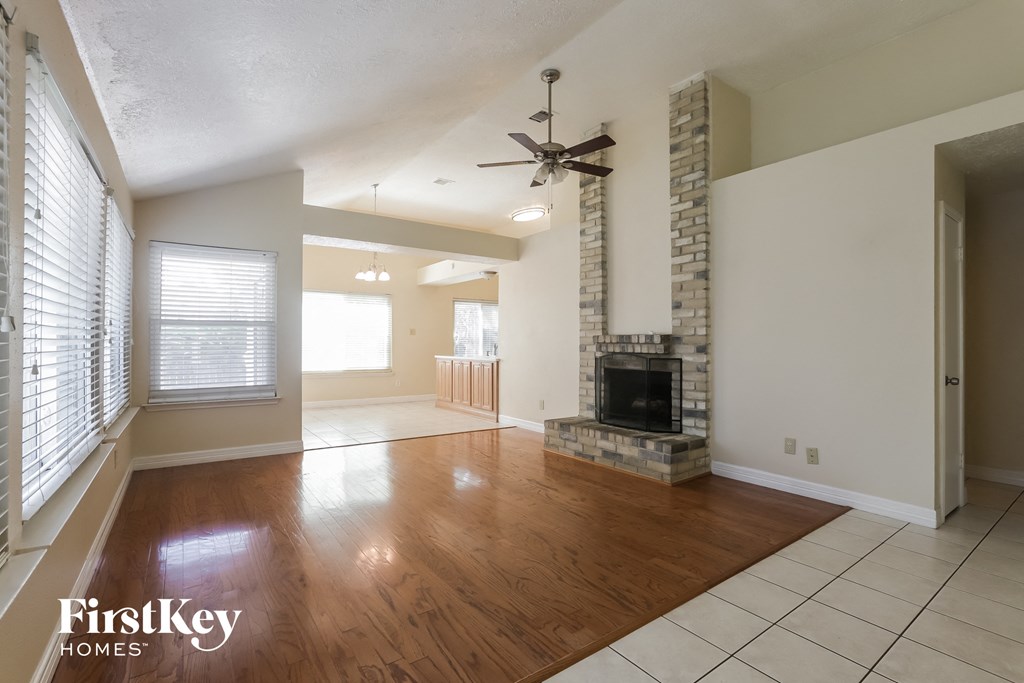 an empty living room with a fireplace and wooden floors