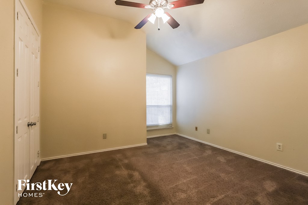 the spacious living room with carpeting and a ceiling fan